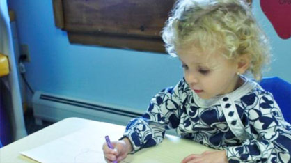 Admissions - picture of a nursery school child at her desk